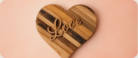 A wooden heart cutting board with "Love" carved in script
